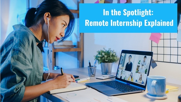A female remote intern working from home desk, looking at an open laptop screen during an online team meeting while writing notes in a notebook.